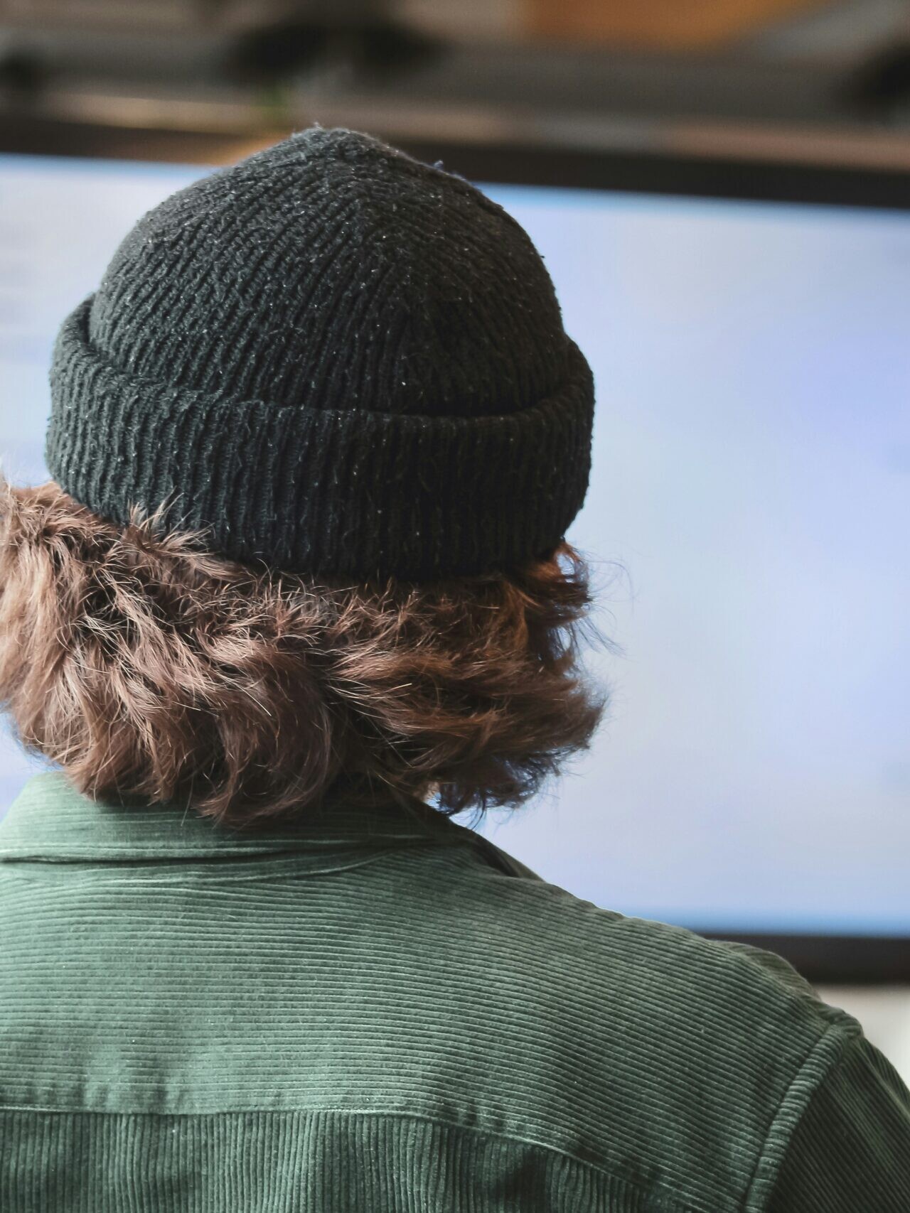 person in green shirt wearing black knit cap