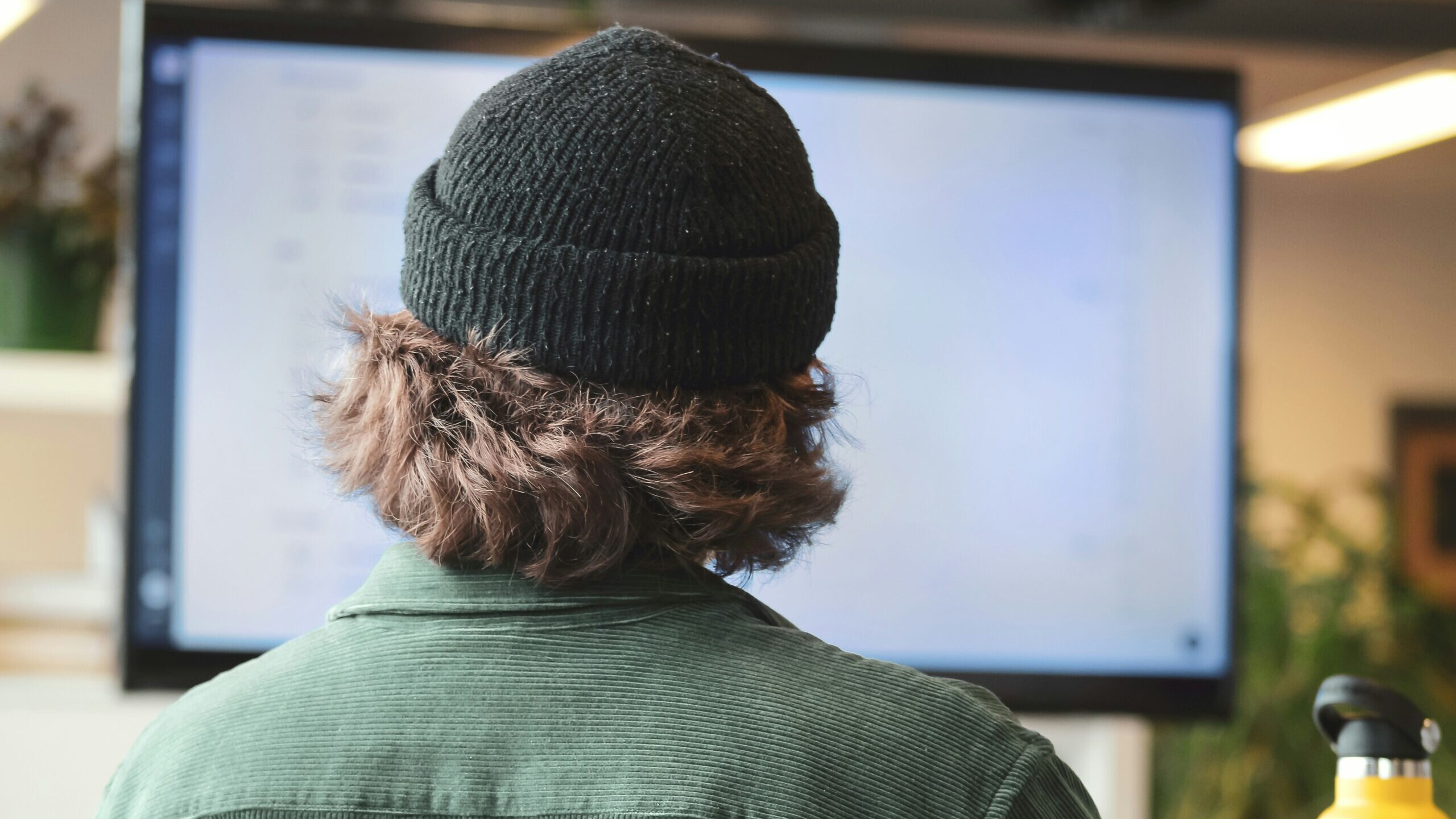 person in green shirt wearing black knit cap
