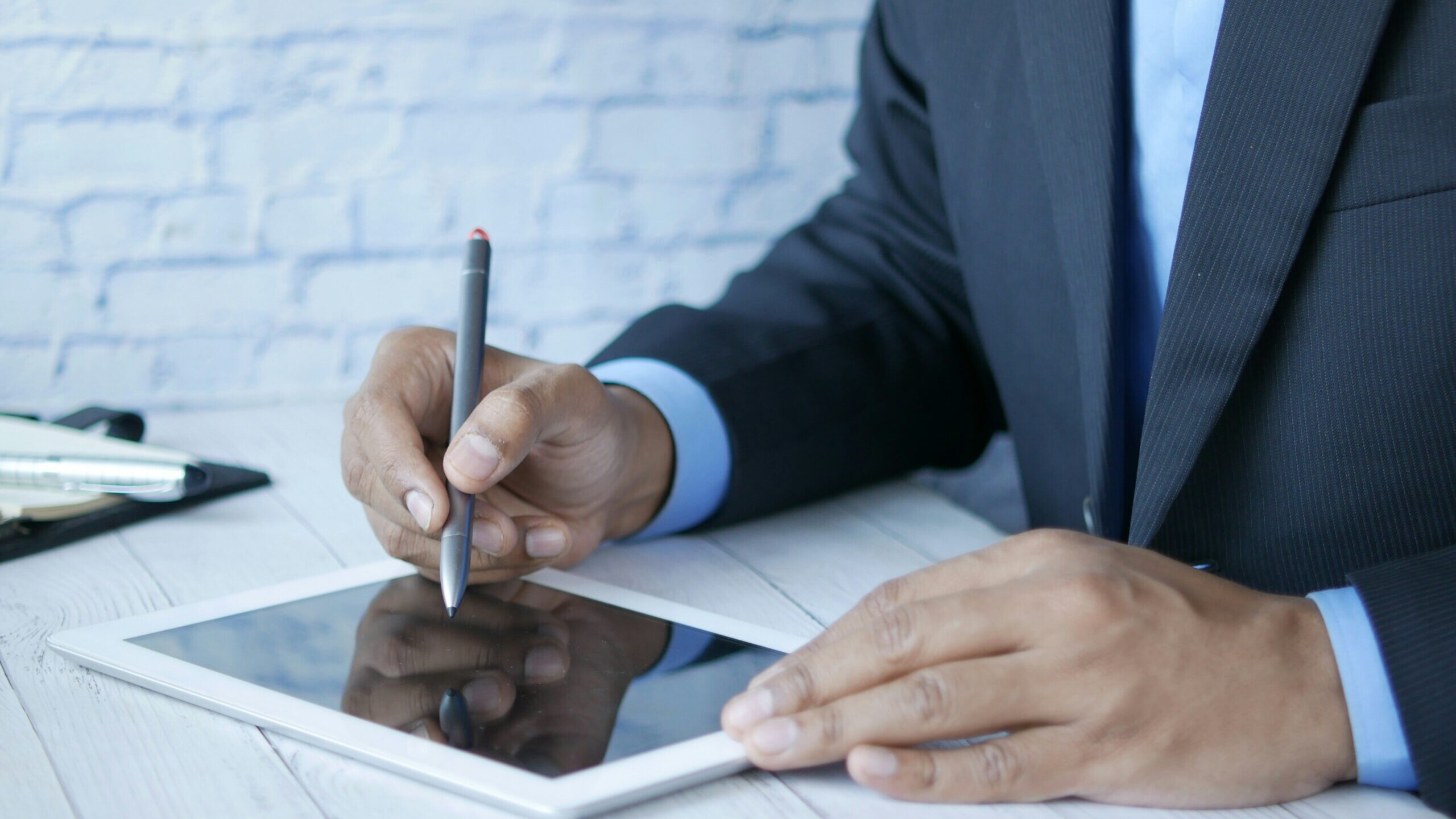 a man in a suit writing on a tablet