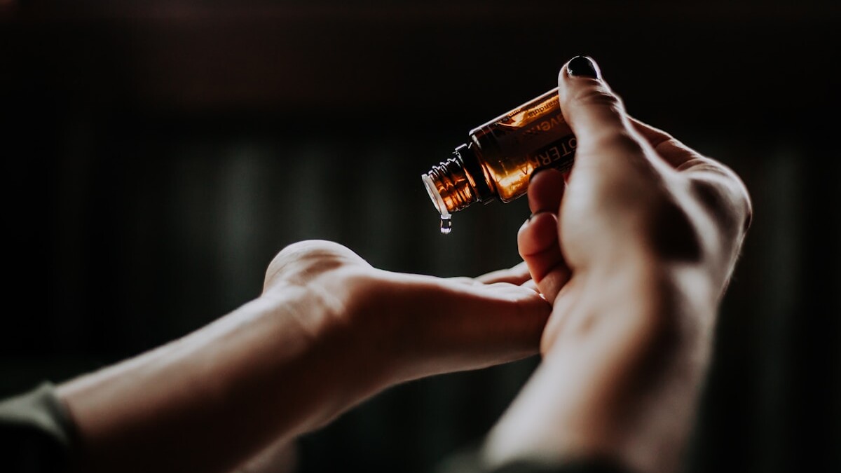 person holding amber glass bottle