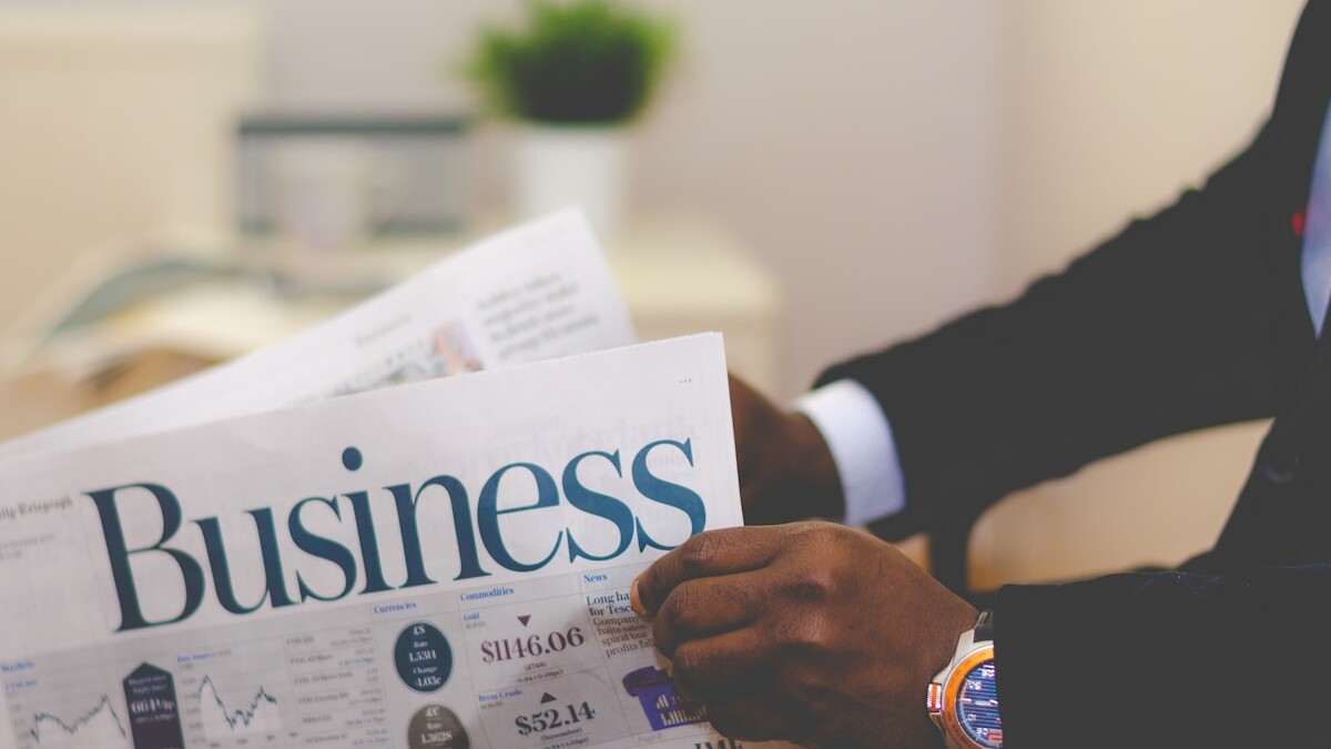 person wearing suit reading business newspaper