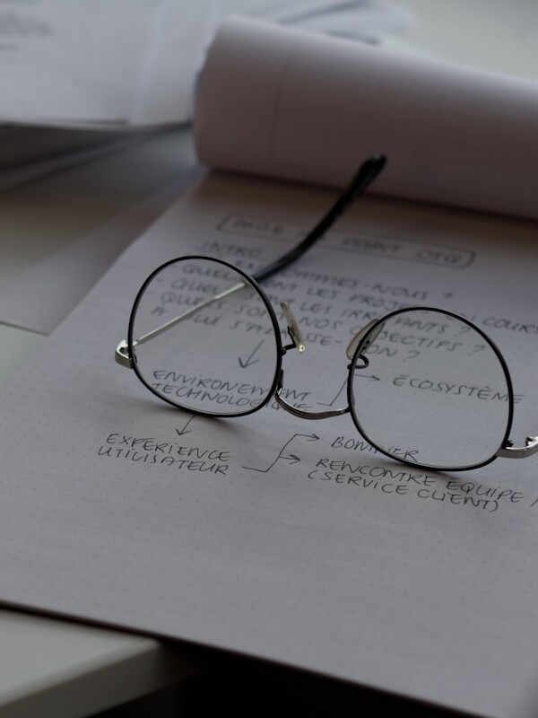 black framed eyeglasses on top of white printing paper