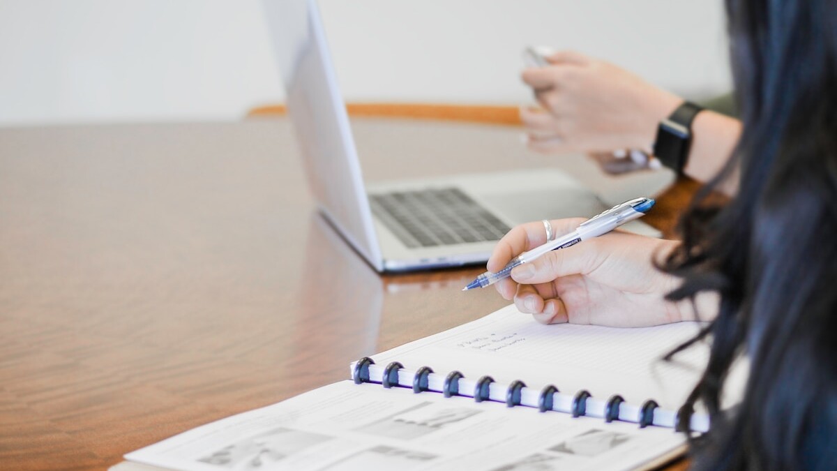 person holding pen writing on paper