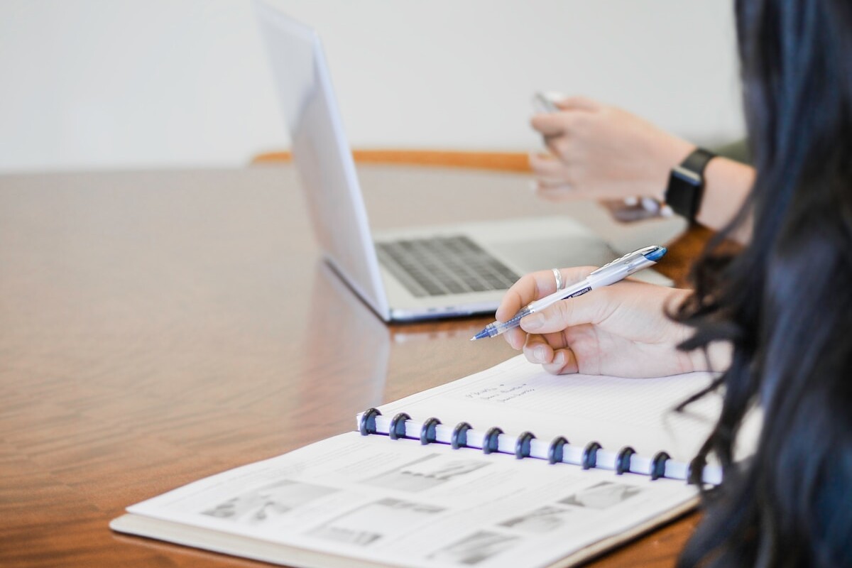 person holding pen writing on paper