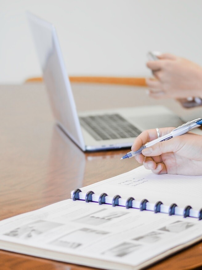 person holding pen writing on paper