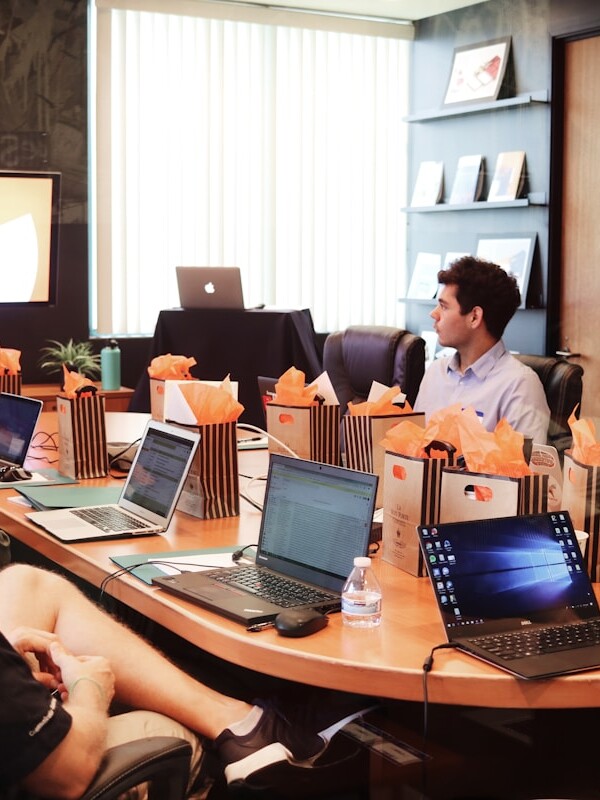 man standing in front of people sitting beside table with laptop computers