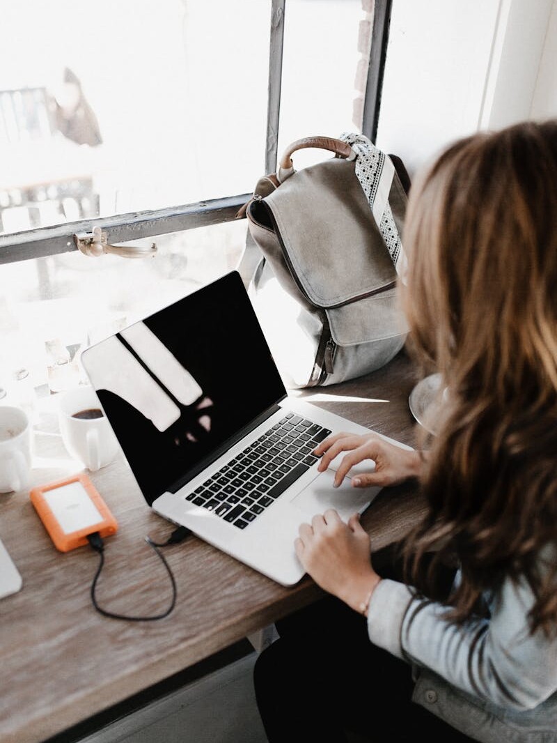 Close-up Photography of Woman Sitting Beside Table While Using Macbook