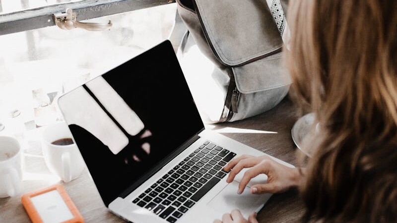 Close-up Photography of Woman Sitting Beside Table While Using Macbook