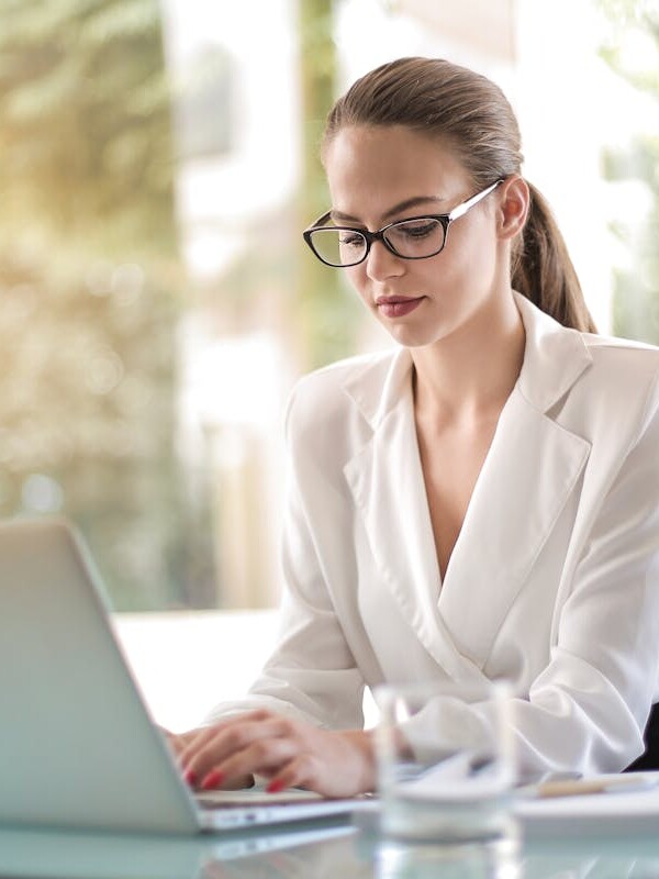 Concentrated female entrepreneur typing on laptop in workplace