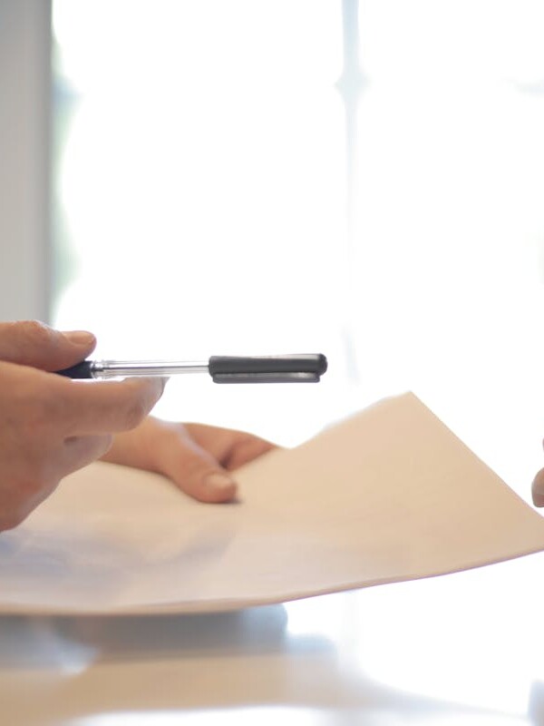 Crop businessman giving contract to woman to sign