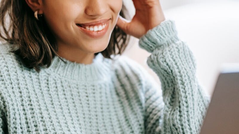 Hispanic woman working remotely on laptop near notepad in apartment