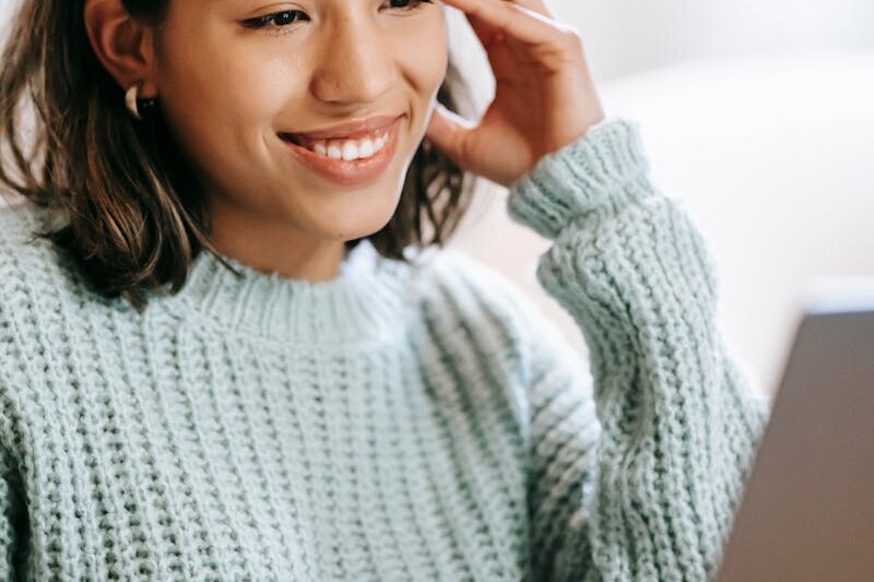 Hispanic woman working remotely on laptop near notepad in apartment