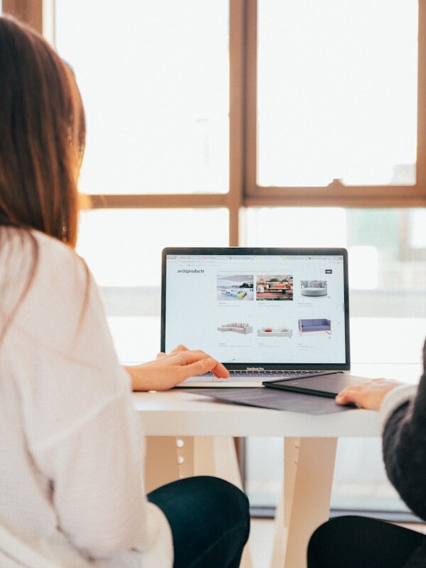 two women talking while looking at laptop computer