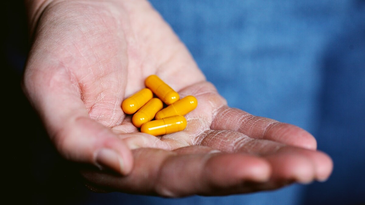 yellow medication pill on persons hand