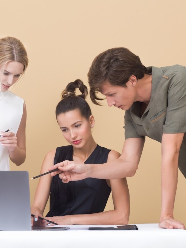 man teaching woman while pointing on gray laptop