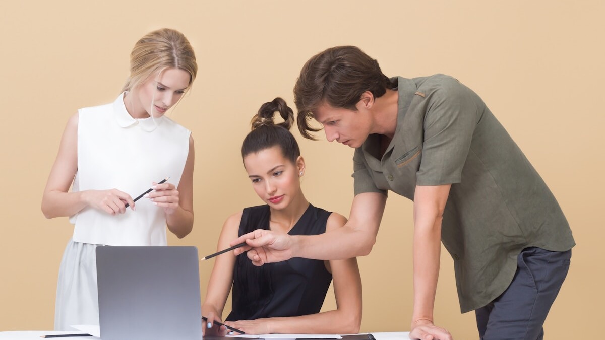 man teaching woman while pointing on gray laptop