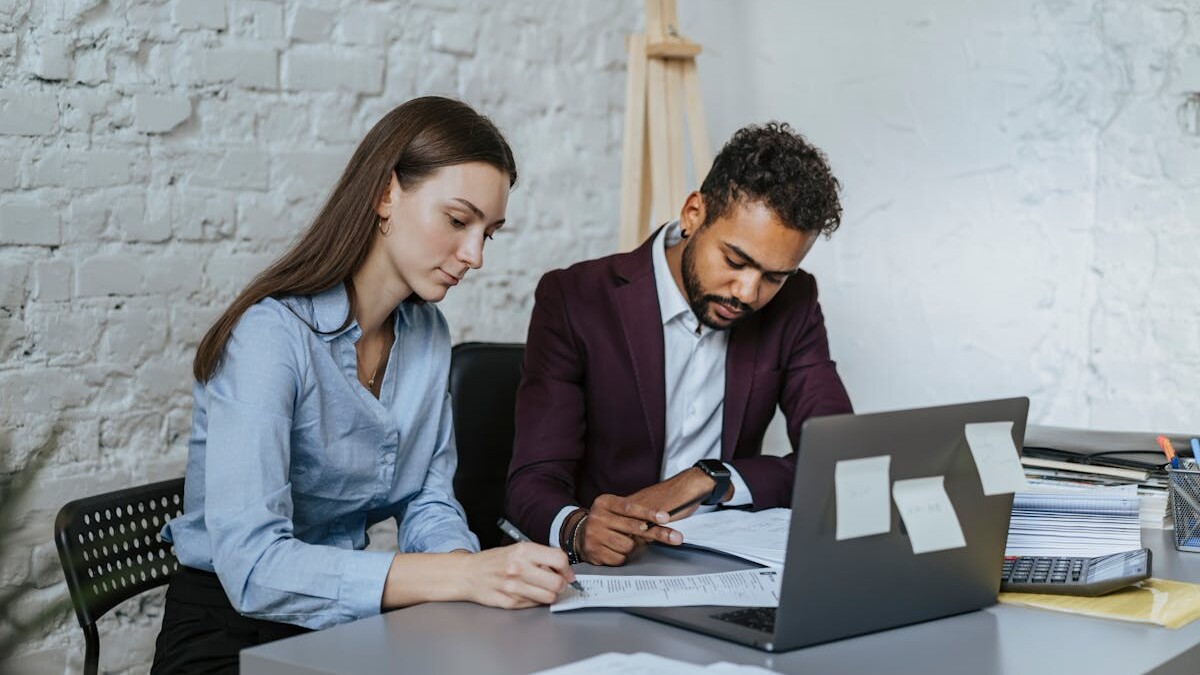 A Man and a Woman Sitting at Table while Working