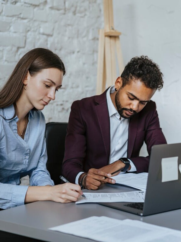 A Man and a Woman Sitting at Table while Working