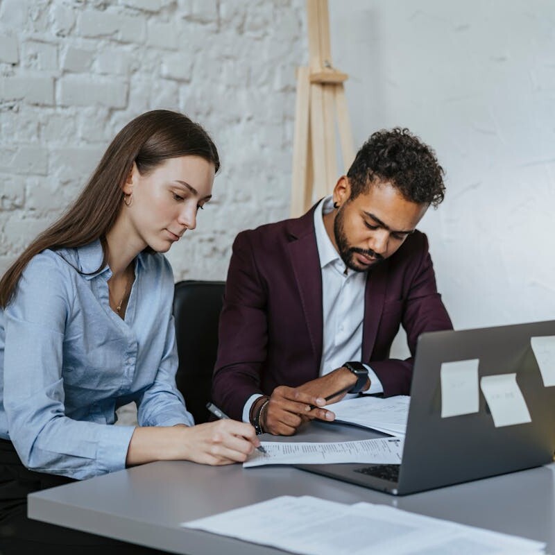 A Man and a Woman Sitting at Table while Working