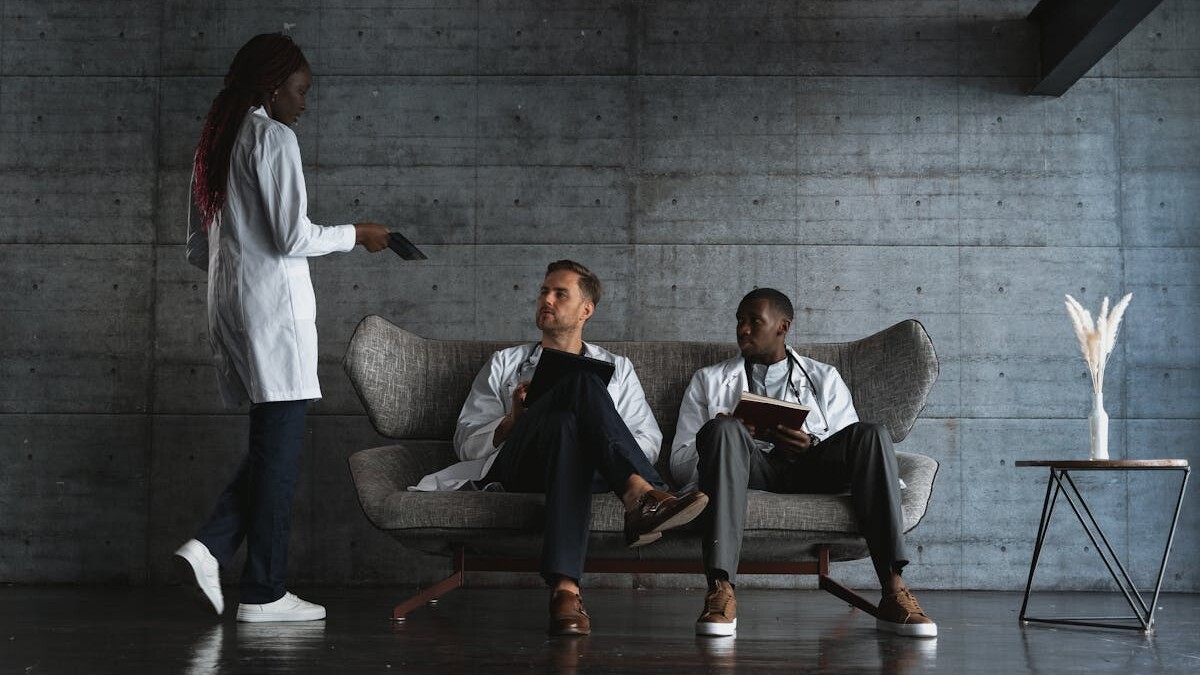 Woman Standing Beside Men Sitting on a Couch