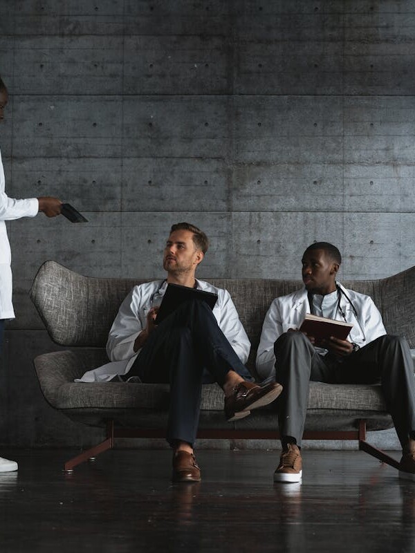 Woman Standing Beside Men Sitting on a Couch