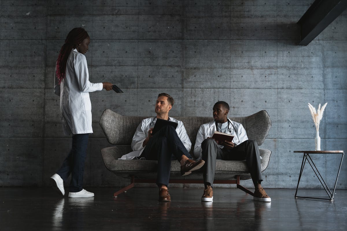 Woman Standing Beside Men Sitting on a Couch