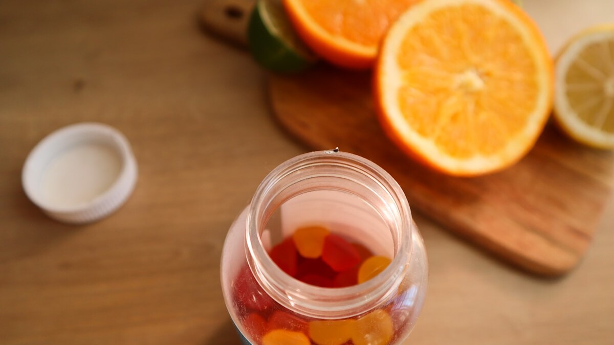 a jar filled with gummy bears next to sliced oranges