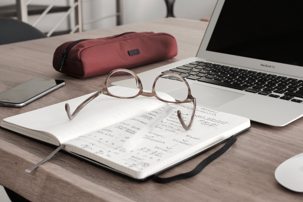 eyeglasses on book beside laptop