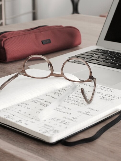 eyeglasses on book beside laptop