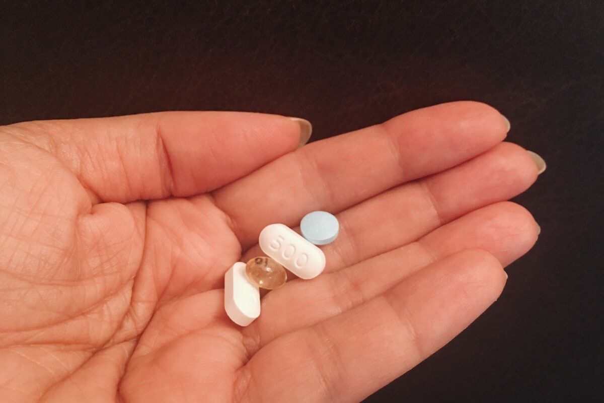 person holding four assorted medicine tablets