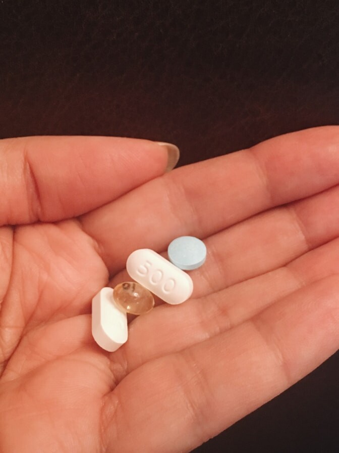 person holding four assorted medicine tablets