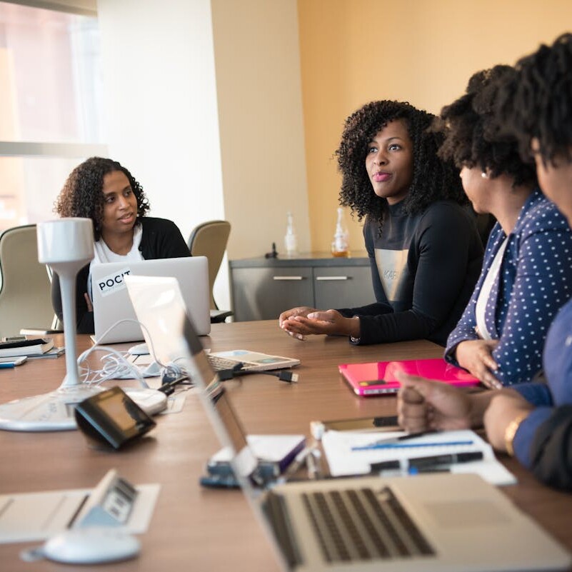 Diverse team of professionals engaging in a collaborative office meeting around a desk.