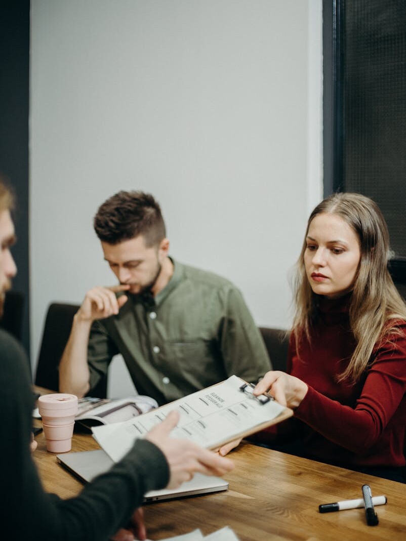 A team of adults discussing documents in an office meeting setting, focusing on collaboration.