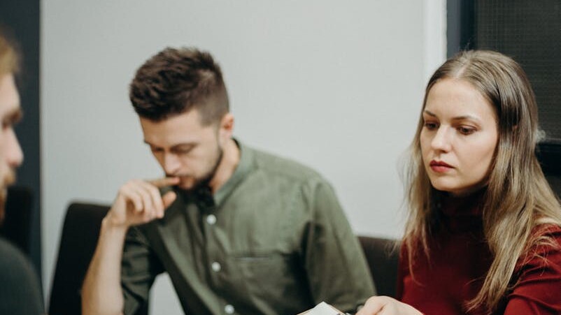 A team of adults discussing documents in an office meeting setting, focusing on collaboration.