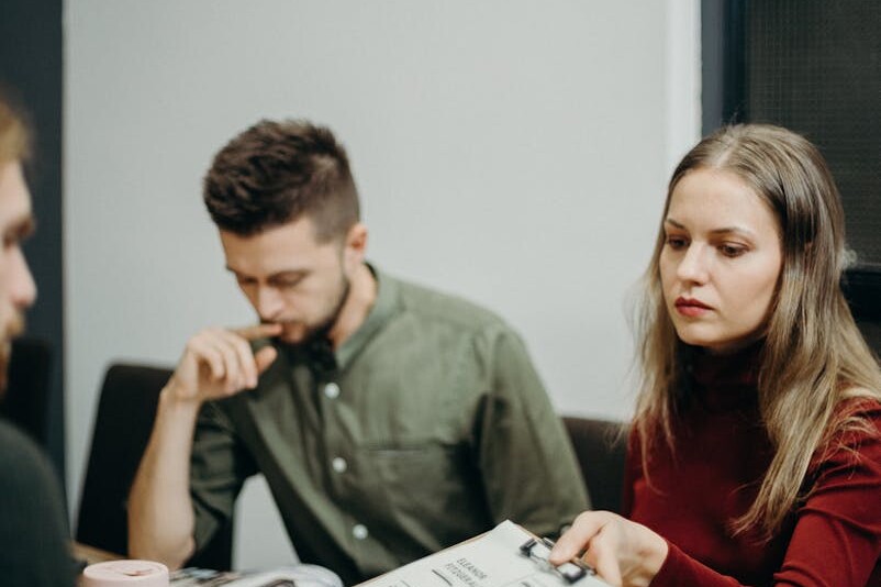 A team of adults discussing documents in an office meeting setting, focusing on collaboration.