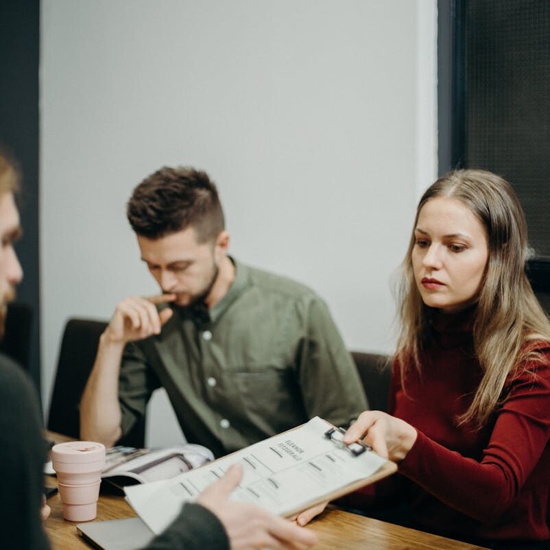 A team of adults discussing documents in an office meeting setting, focusing on collaboration.