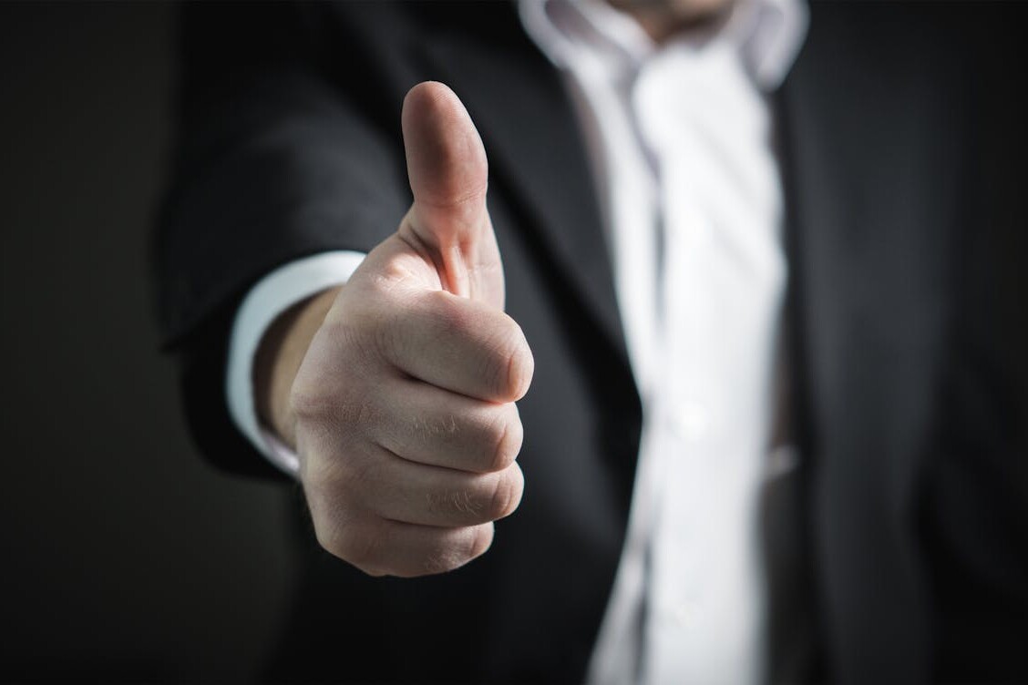 A close-up of a man's thumbs up gesture, symbolizing success and agreement.