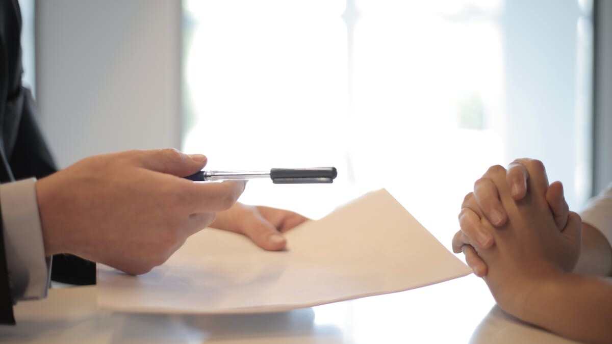 Close-up of a contract signing with hands over documents. Professional business interaction.