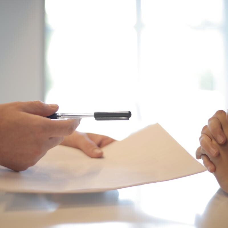 Close-up of a contract signing with hands over documents. Professional business interaction.