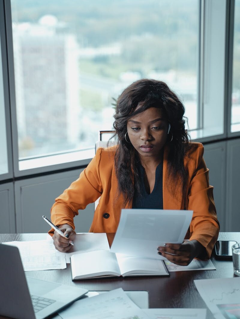 Professional woman in a bright office reviewing paperwork. Productivity and focus in a business setting.