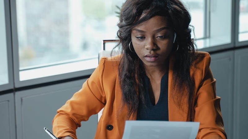 Professional woman in a bright office reviewing paperwork. Productivity and focus in a business setting.