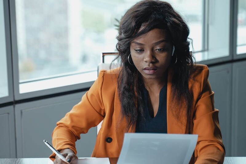 Professional woman in a bright office reviewing paperwork. Productivity and focus in a business setting.