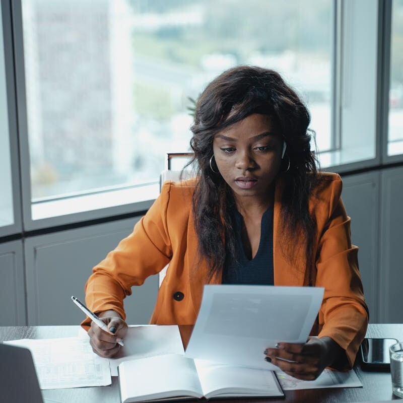 Professional woman in a bright office reviewing paperwork. Productivity and focus in a business setting.