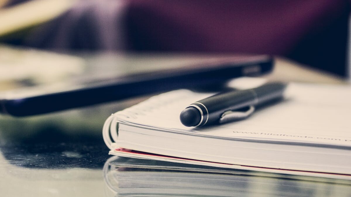 Close-up of an elegant pen resting on an open notebook in a stylish office environment.