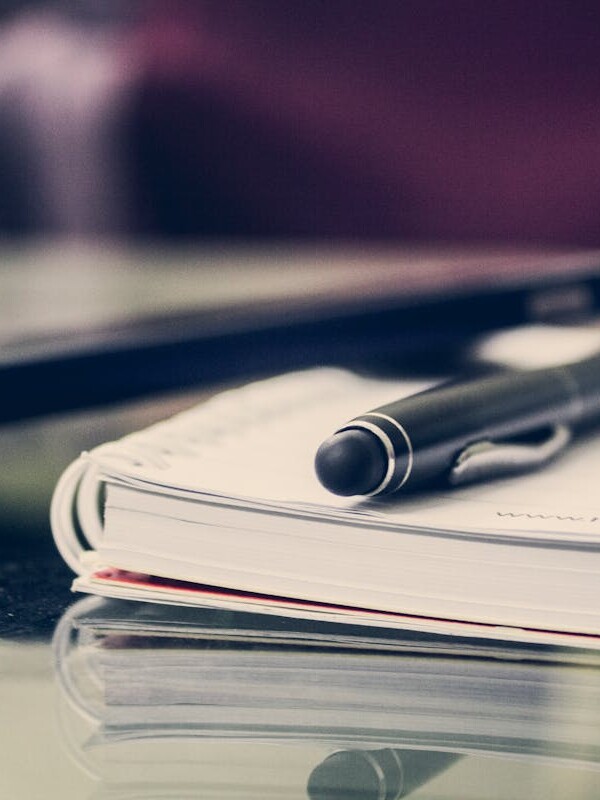 Close-up of an elegant pen resting on an open notebook in a stylish office environment.