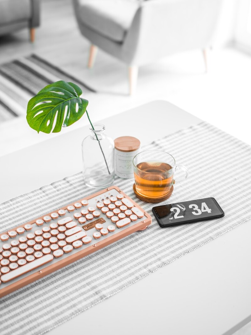 brown computer keyboard beside glass mug