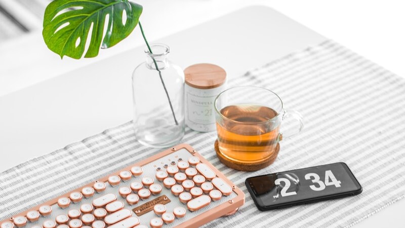 brown computer keyboard beside glass mug