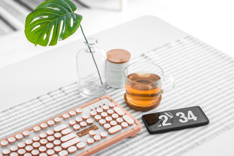 brown computer keyboard beside glass mug