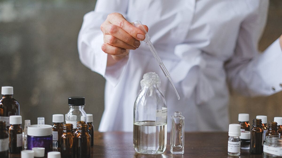 Scientist using a dropper to mix liquids in glass bottles, showcasing a laboratory setting.