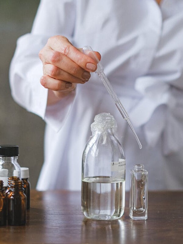 Scientist using a dropper to mix liquids in glass bottles, showcasing a laboratory setting.